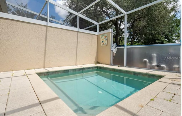 view of swimming pool featuring a patio area and glass enclosure