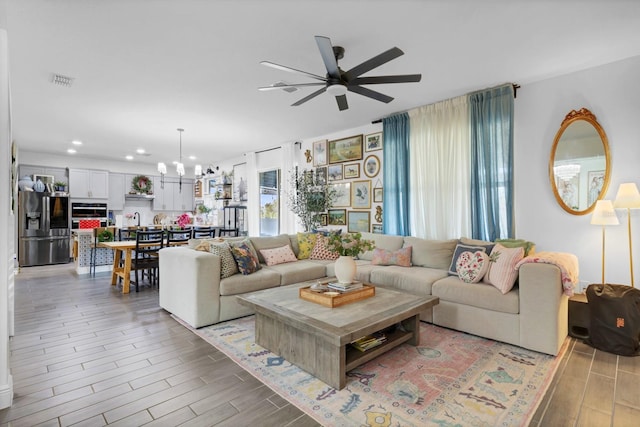 living room featuring ceiling fan with notable chandelier