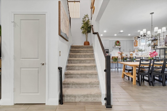 stairway featuring a notable chandelier