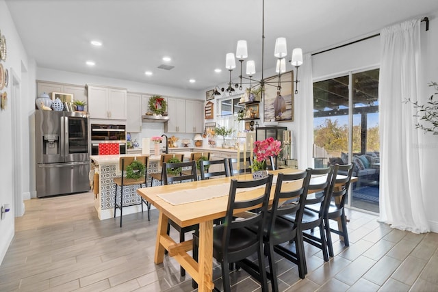 dining area featuring sink, light hardwood / wood-style flooring, and a notable chandelier