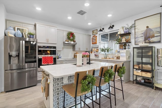 kitchen with a kitchen bar, a center island, stainless steel appliances, light stone countertops, and decorative backsplash