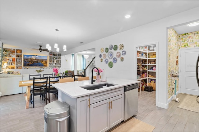 kitchen featuring sink, gray cabinetry, hanging light fixtures, a center island with sink, and dishwasher