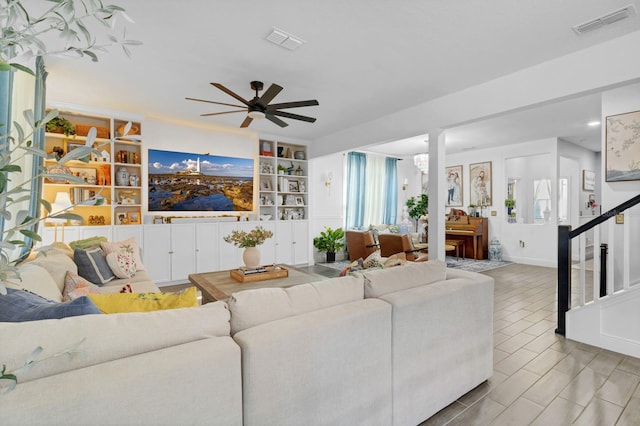 living room with built in shelves and ceiling fan