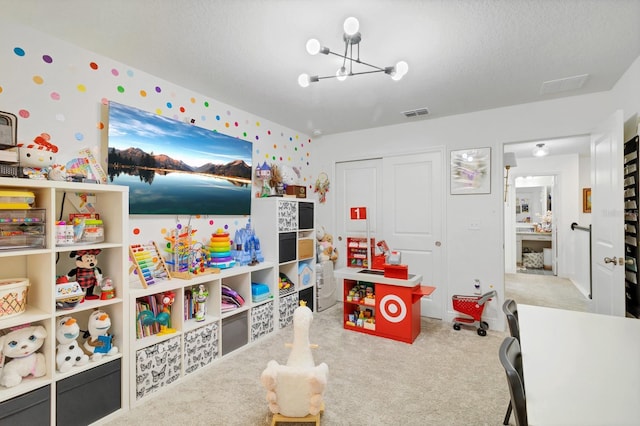 rec room with a chandelier, light carpet, and a textured ceiling