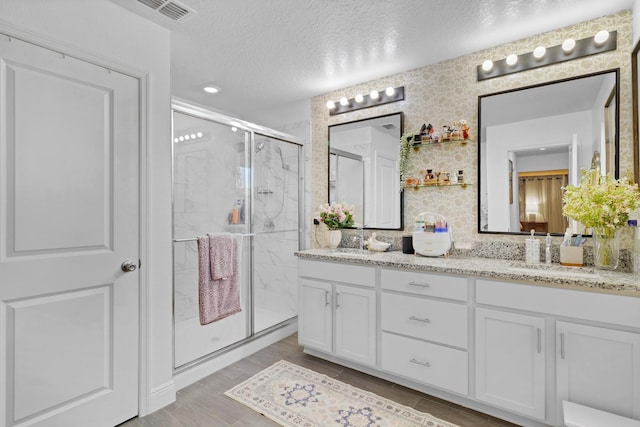 bathroom with vanity, hardwood / wood-style floors, a textured ceiling, and a shower with shower door