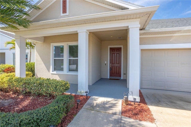 doorway to property featuring a garage, driveway, and stucco siding