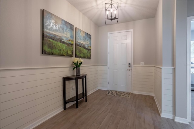 foyer entrance featuring a notable chandelier, wainscoting, and wood finished floors