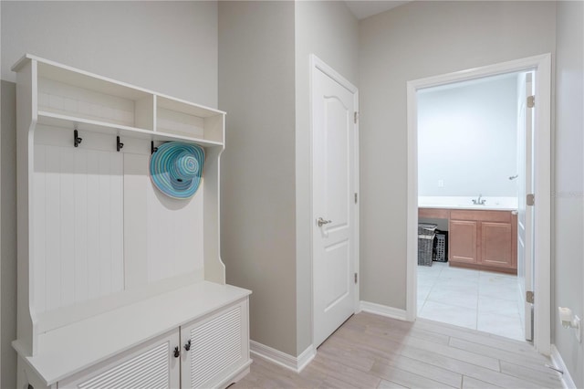 mudroom with a sink, light wood-type flooring, and baseboards