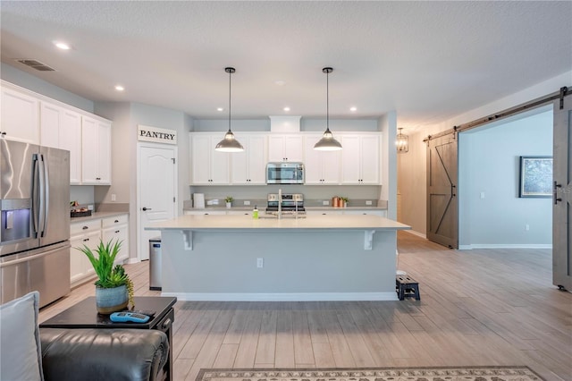 kitchen with stainless steel appliances, a barn door, visible vents, and light countertops