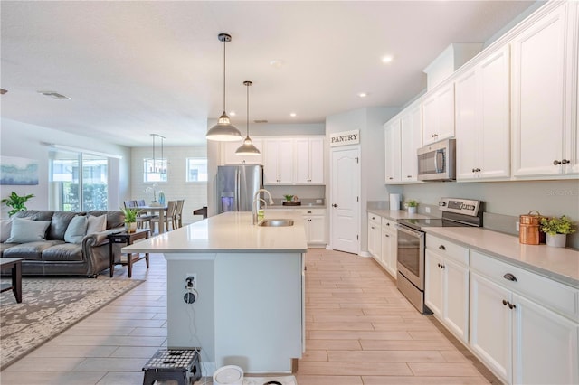 kitchen with visible vents, a sink, stainless steel appliances, white cabinetry, and open floor plan