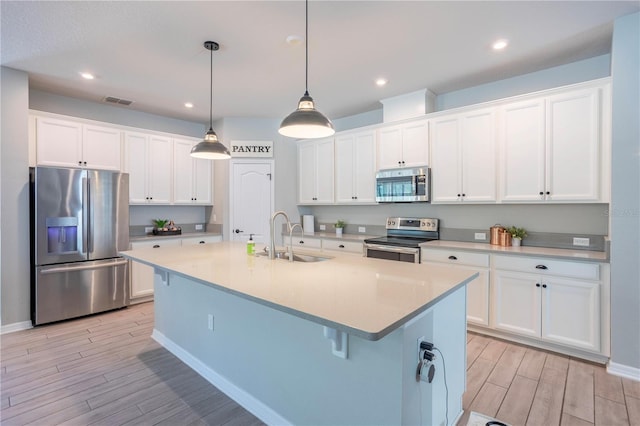 kitchen with a sink, stainless steel appliances, wood finish floors, and white cabinets