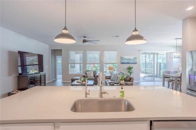 kitchen featuring visible vents, open floor plan, an island with sink, hanging light fixtures, and a sink