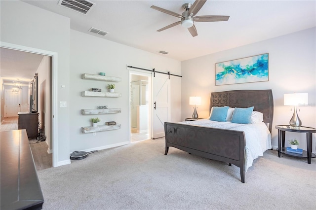 bedroom featuring a barn door, light carpet, and visible vents