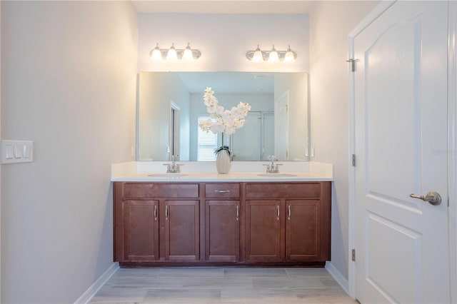 full bath featuring a sink, baseboards, and double vanity