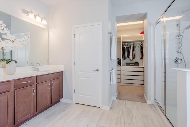 bathroom with vanity, a spacious closet, baseboards, and a stall shower