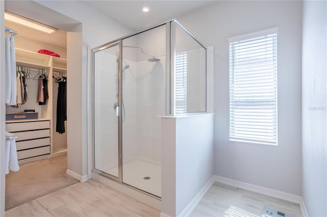 bathroom with a spacious closet, baseboards, and a stall shower