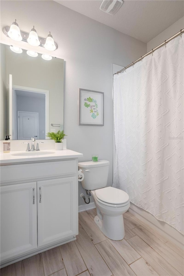 full bath featuring visible vents, toilet, vanity, and wood finished floors