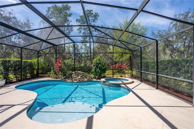 view of pool with a patio area, glass enclosure, and a pool with connected hot tub