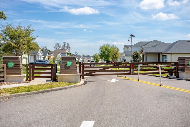 view of road with a residential view, a gated entry, street lighting, and a gate