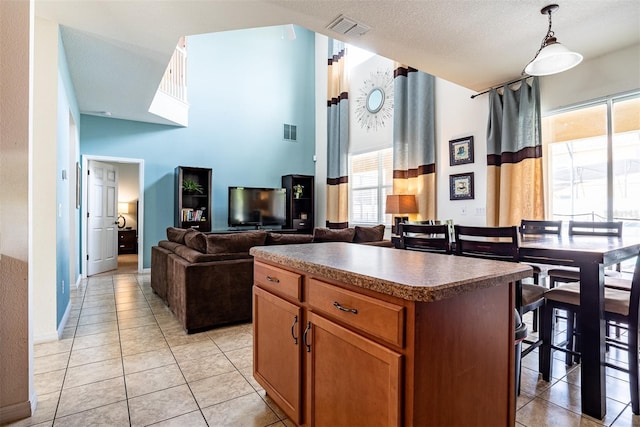 kitchen featuring a high ceiling, a center island, pendant lighting, and light tile patterned floors