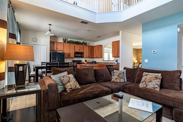 living room with a towering ceiling and light tile patterned flooring