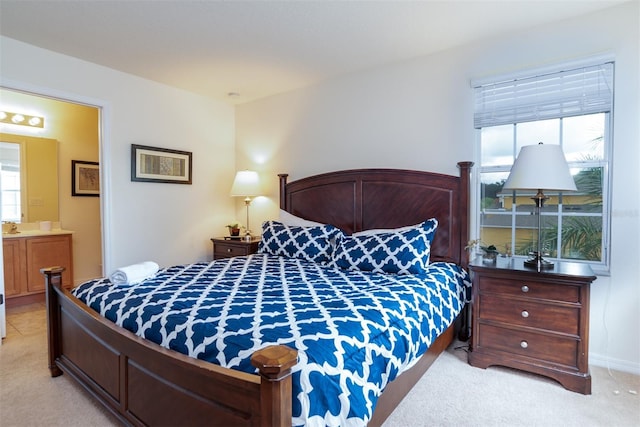 carpeted bedroom featuring multiple windows and ensuite bath