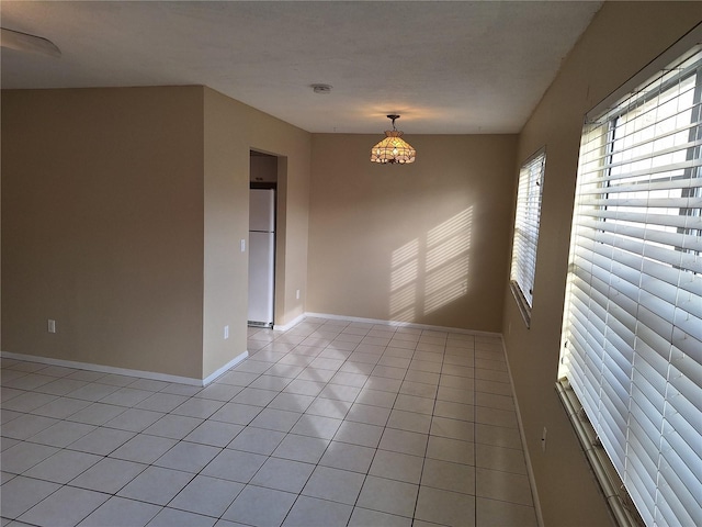 tiled spare room with a notable chandelier