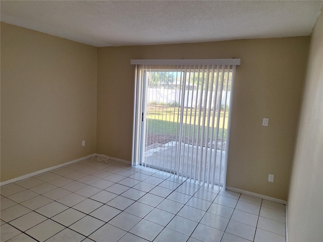 tiled empty room featuring a textured ceiling