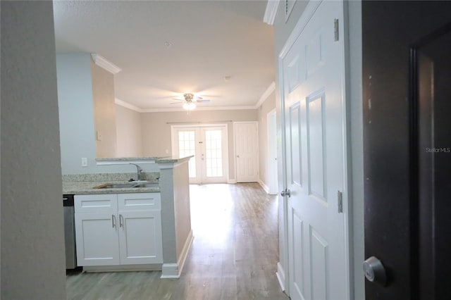 kitchen featuring ornamental molding, sink, white cabinets, and light hardwood / wood-style floors