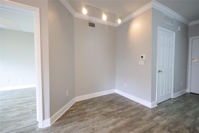 spare room with ornamental molding, dark wood-type flooring, and track lighting