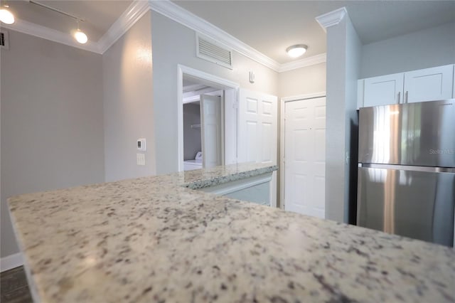 kitchen with ornamental molding, stainless steel fridge, light stone countertops, and white cabinets