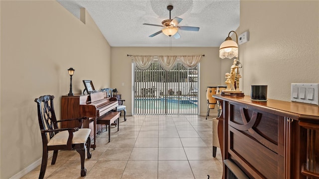 sitting room with ceiling fan, a textured ceiling, and light tile patterned floors