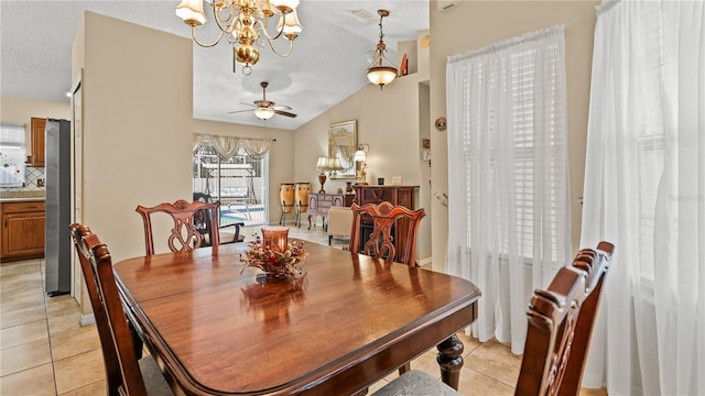 dining space featuring lofted ceiling, ceiling fan with notable chandelier, a textured ceiling, and light tile patterned floors