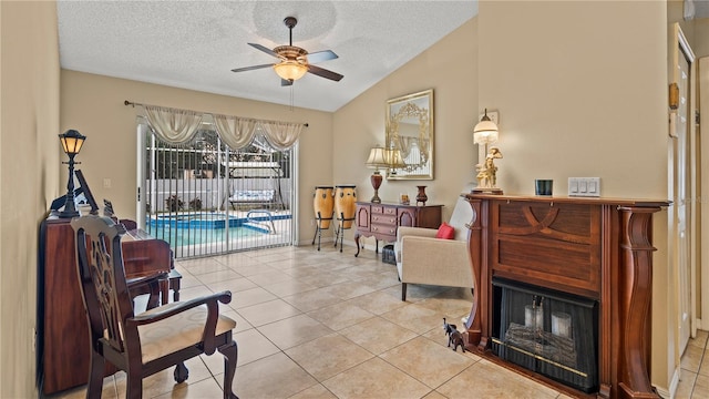 sitting room featuring light tile patterned floors, vaulted ceiling, a textured ceiling, and ceiling fan