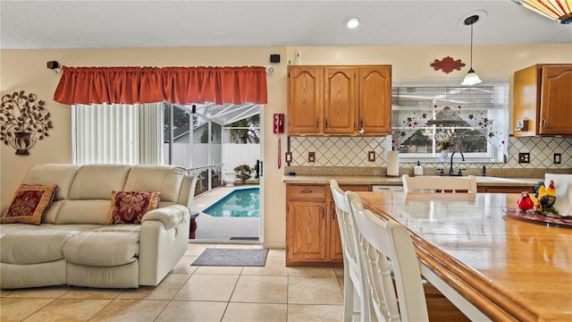 kitchen featuring light tile patterned flooring, a healthy amount of sunlight, backsplash, and decorative light fixtures