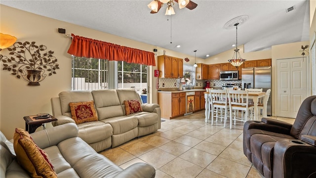 tiled living room featuring ceiling fan, lofted ceiling, and a textured ceiling