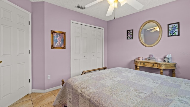 tiled bedroom with ceiling fan, a closet, and a textured ceiling