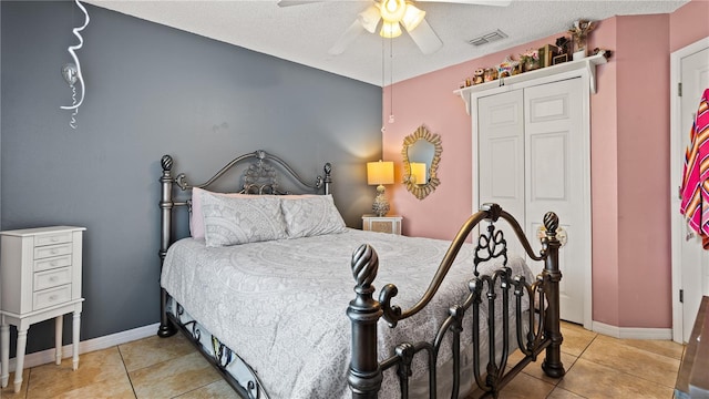 tiled bedroom with ceiling fan, a textured ceiling, and a closet