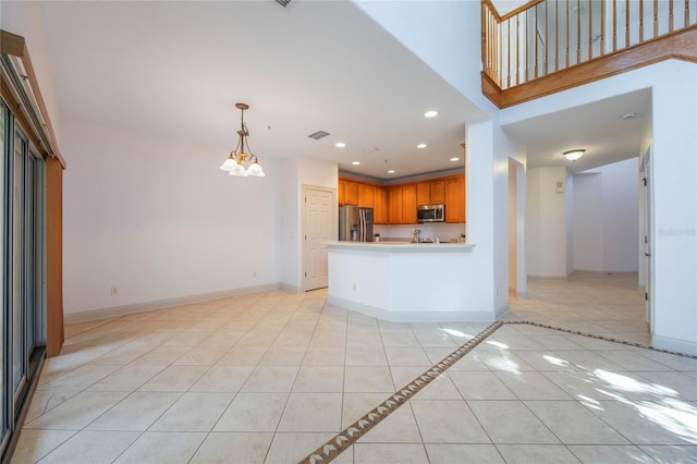 kitchen with pendant lighting, light tile patterned floors, an inviting chandelier, a towering ceiling, and stainless steel appliances