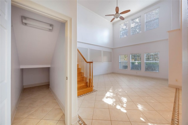 staircase with a towering ceiling, tile patterned floors, and ceiling fan