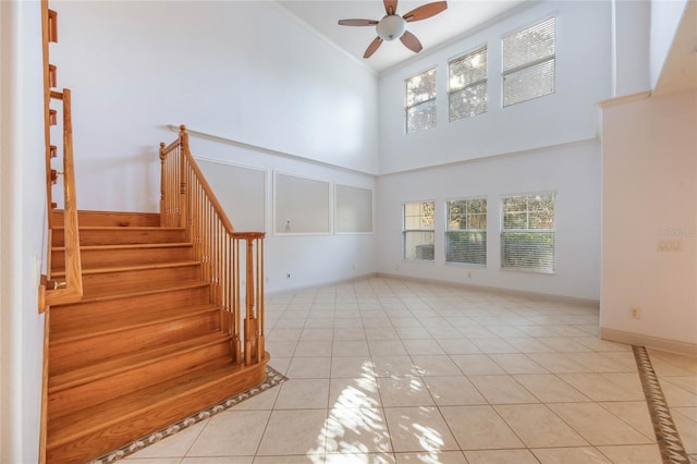 staircase featuring a high ceiling, a healthy amount of sunlight, tile patterned floors, and ceiling fan