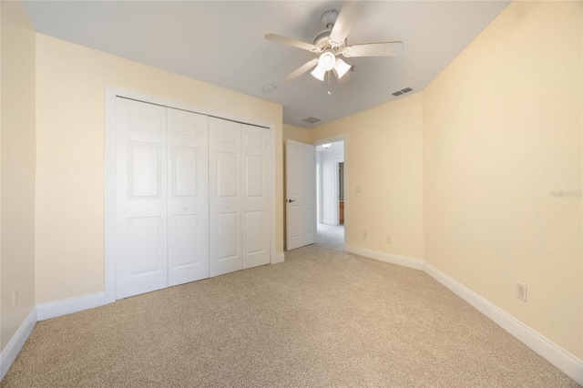 unfurnished bedroom featuring ceiling fan, light colored carpet, and a closet