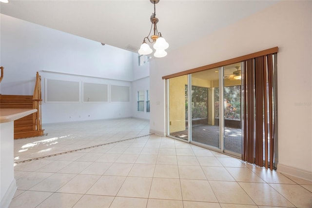 tiled empty room with a high ceiling and an inviting chandelier