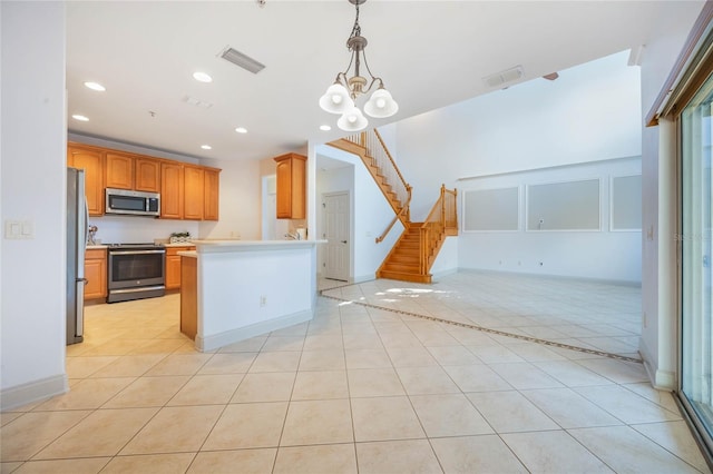 kitchen with stainless steel appliances, light tile patterned flooring, pendant lighting, and a notable chandelier