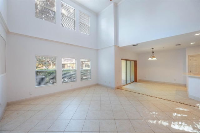 unfurnished living room featuring a towering ceiling and light tile patterned floors