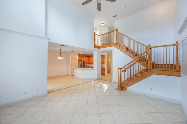 unfurnished living room featuring light tile patterned flooring, ceiling fan, and a high ceiling