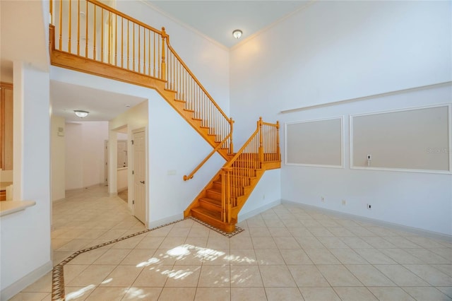 stairs with crown molding, a towering ceiling, and tile patterned floors