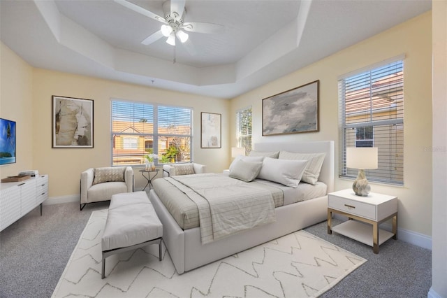 bedroom featuring light colored carpet, a raised ceiling, and ceiling fan