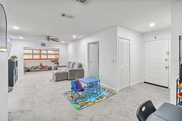 playroom featuring ceiling fan, light carpet, and a textured ceiling