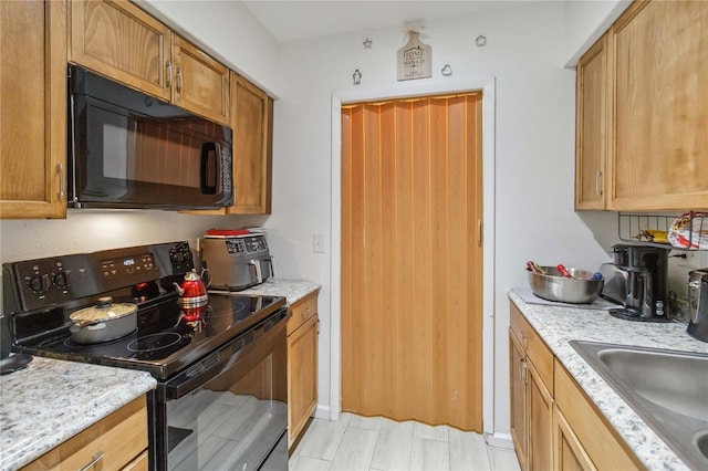 kitchen with light stone counters, sink, and black appliances